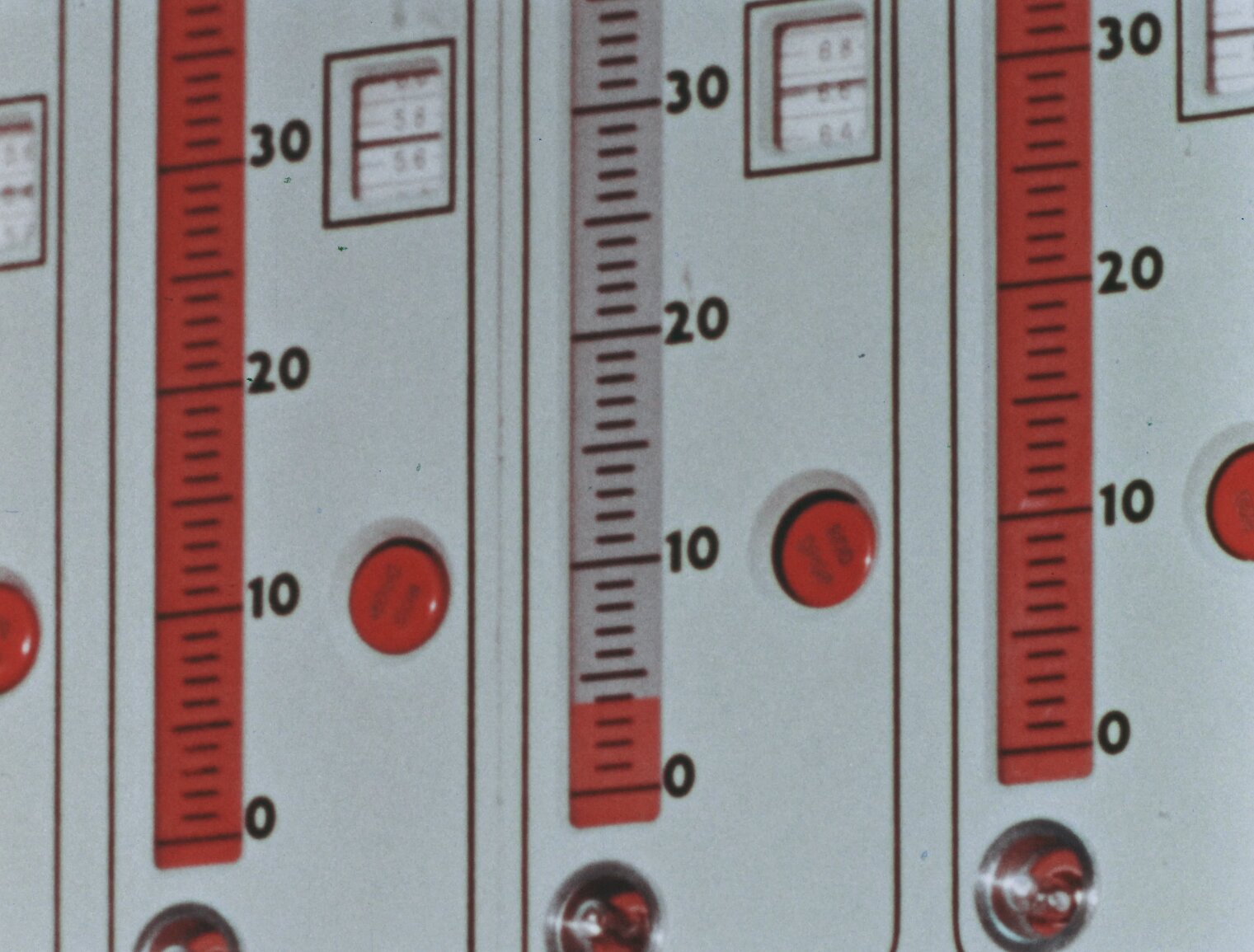 Closeup of control rod position indicators, which are red and white ruler-like indicators with red buttons and indicator lights. There are three of them shown.