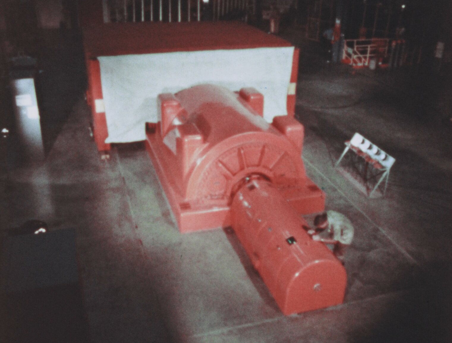 The Bonus turbine generator, an orange set of cylindars mounted in concrete with a technician bending over one.