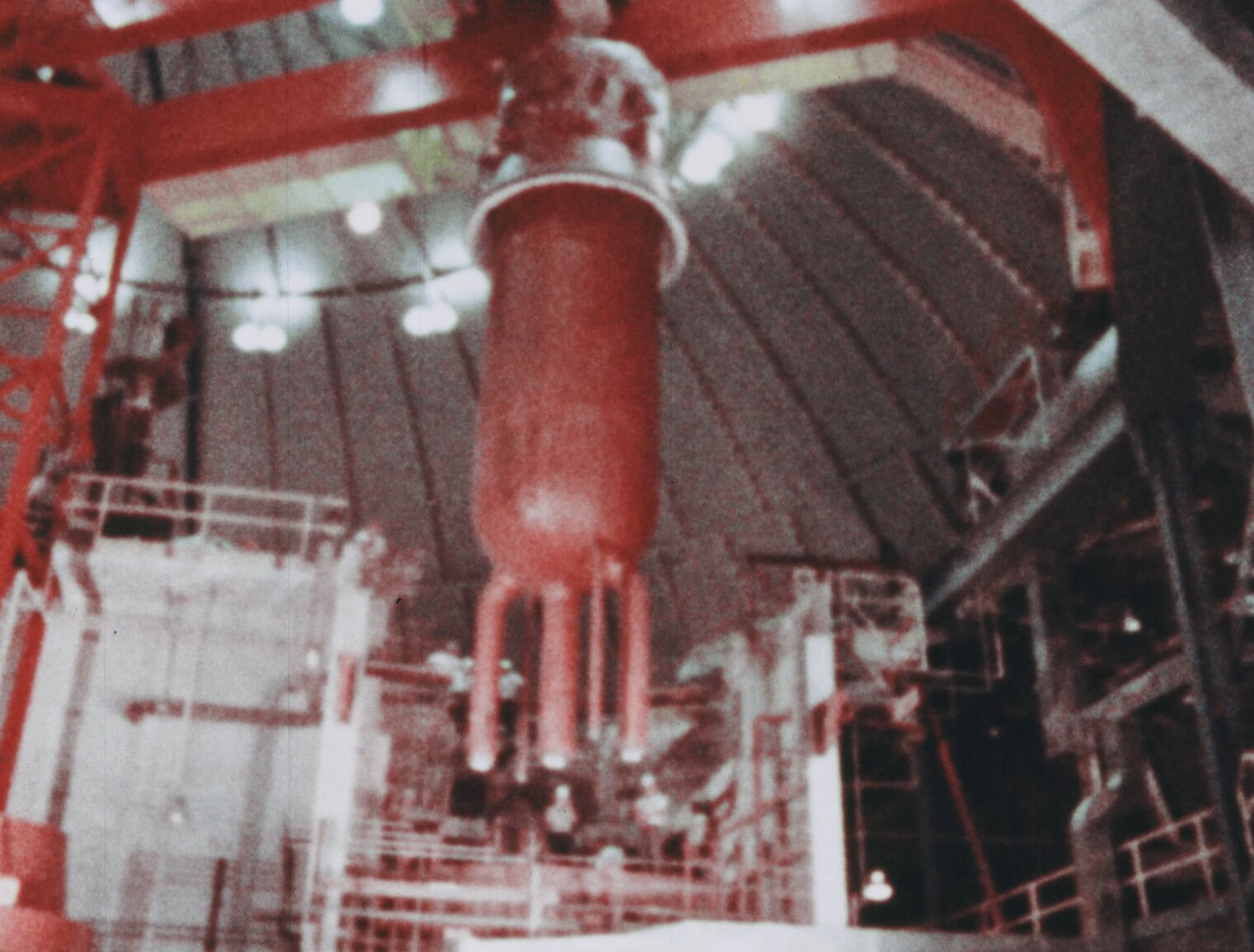 Pressure vessel in BONUS dome now being lifted by large internal crane. Several men in hardhats are seen in the background
