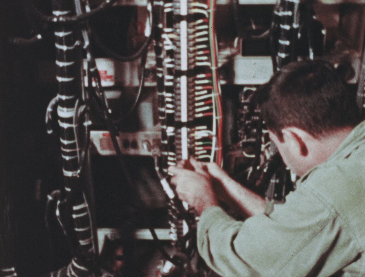 Technician attaches many red and green and black wires to a connection terminal of some kind.